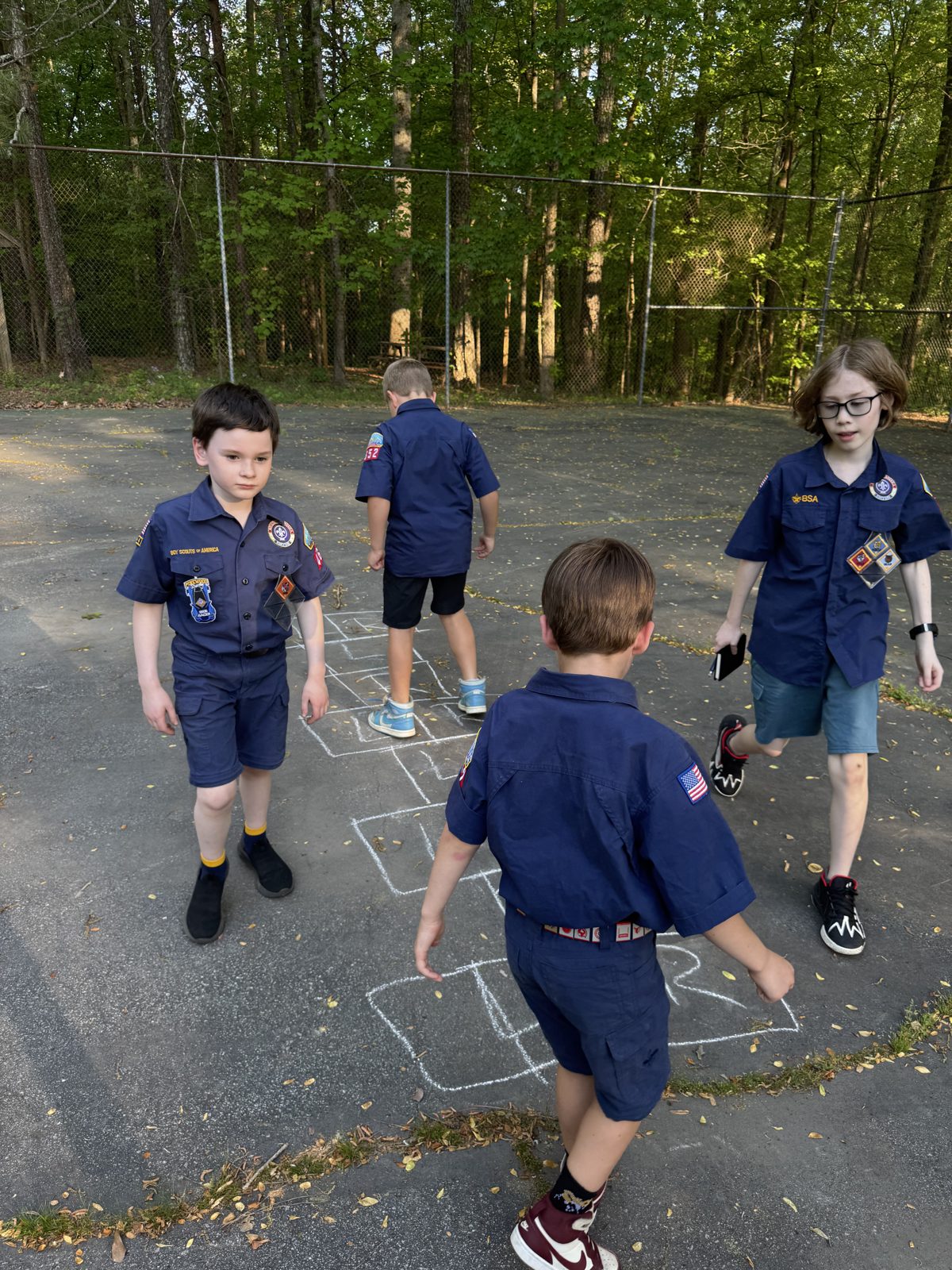 Scouts in uniform playing a hopscotch game outside
