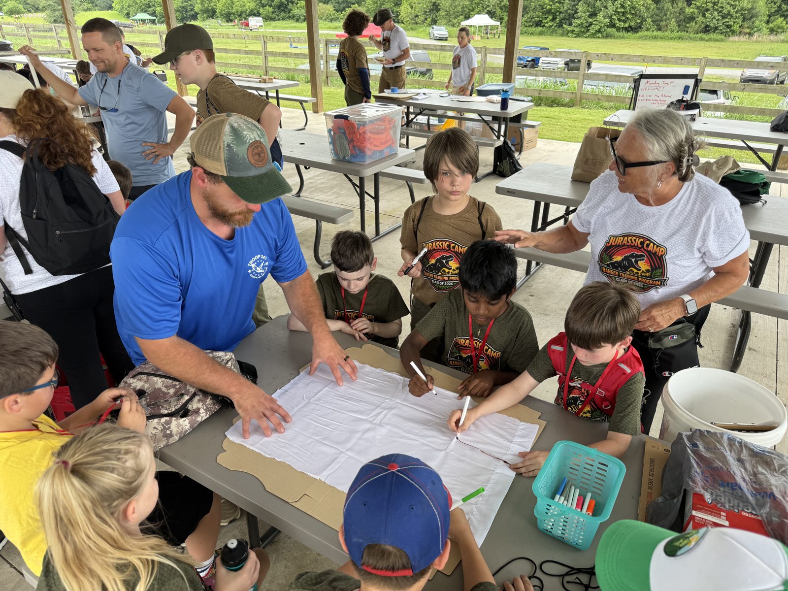 Scouts and leaders working on a craft project at an outdoor pavilion
